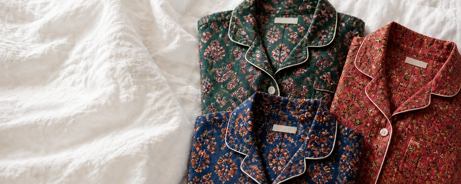 Folded pajamas with emerald, cobalt and raspberry botanical prints on white linen